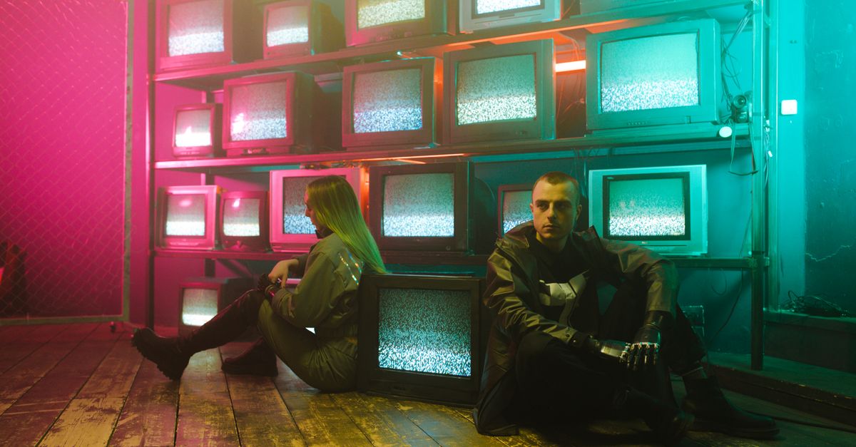 Two individuals in a cyberpunk setting with neon lighting and stacked television screens.